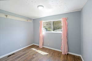 Empty room with baseboards, wood finished floors, and visible vents