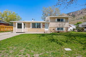 Split level home featuring fence, a front lawn, entry steps, and brick siding
