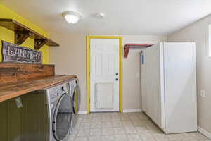 Washroom featuring light floors, washing machine and dryer, baseboards, and laundry area