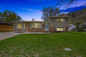 Tri-level home featuring brick siding, a yard, entry steps, and fence
