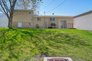Rear view of house with brick siding, a lawn, fence, and a gate