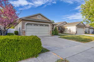 Ranch-style house featuring an attached garage, driveway, stone siding, and stucco siding