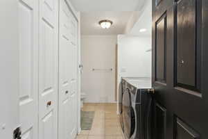 Laundry area with baseboards, washer and clothes dryer, laundry area, and light tile patterned floors