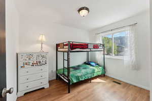 Bedroom with wood finished floors, visible vents, and baseboards