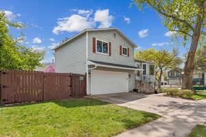 Split level home with a gate, fence, an attached garage, driveway, and a front yard