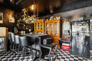 Bar featuring freestanding refrigerator, tile patterned floors, and a bar