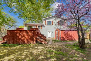 Rear view of property with a wooden deck, a storage unit, stairs, and an outdoor structure