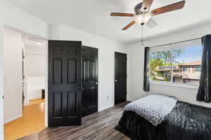 Bedroom with dark wood-type flooring, multiple closets, baseboards, and ceiling fan