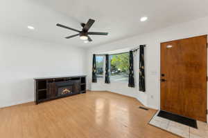 Entryway featuring light wood finished floors, a glass covered fireplace, visible vents, recessed lighting, and a ceiling fan