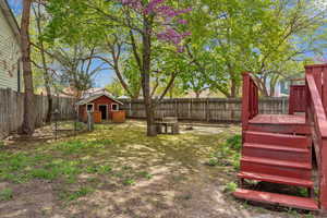 View of yard featuring a fenced backyard, an outdoor structure, a storage shed, and a deck