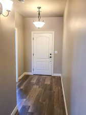 Entryway with baseboards and dark wood-style flooring