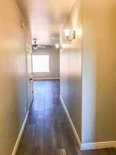 Corridor featuring baseboards and dark wood-style floors