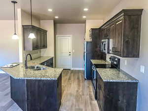 Kitchen with a peninsula, a sink, freestanding refrigerator, light stone countertops, and range with electric stovetop