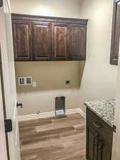 Laundry area with cabinet space, light wood finished floors, baseboards, gas dryer hookup, and washer hookup