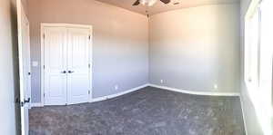 Spare room featuring vaulted ceiling, a ceiling fan, baseboards, dark colored carpet, and visible vents