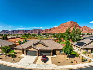 View of front facade with an attached garage, stone siding, driveway, and a mountain view