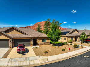 Ranch-style home featuring stone siding, driveway, a garage, and stucco siding