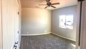 Empty room featuring baseboards, dark colored carpet, visible vents, and a ceiling fan