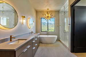 Bathroom with double vanity, a sink, a shower stall, and a freestanding bath