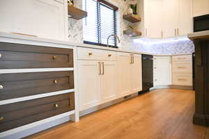 Kitchen featuring open shelves, light wood finished floors, and tasteful backsplash