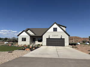 View of front facade featuring stucco siding, stone siding, concrete driveway, an attached garage, and a shingled roof