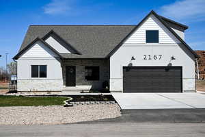 Modern farmhouse with concrete driveway, stucco siding, stone siding, and a garage