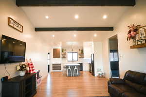 Living area with light wood finished floors, lofted ceiling with beams, plenty of natural light, baseboards, and recessed lighting