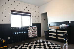 Carpeted bedroom with wainscoting and a decorative wall