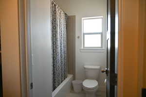 Bathroom featuring shower / bathtub combination with curtain and toilet