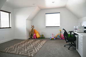 Home office with vaulted ceiling, baseboards, and carpet floors
