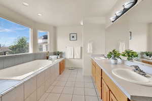 Primary bathroom featuring tile patterned floors, a garden tub, a sink, and double vanity