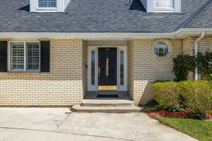Entrance to property with a shingled roof and brick siding