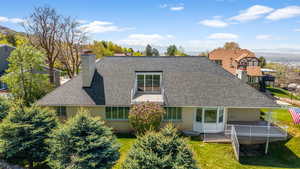 Rear view of house with brick siding, a lawn, a shingled roof, and a chimney