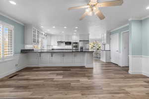 Kitchen featuring stainless steel appliances, a peninsula, dark countertops, recessed lighting, and glass insert cabinets