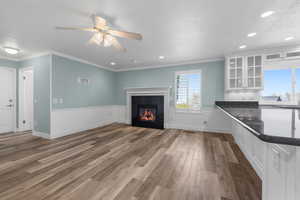 Unfurnished living room with a ceiling fan, crown molding, a tiled fireplace, and recessed lighting