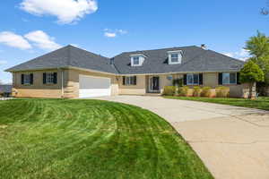 Traditional-style house with brick siding, driveway, a front yard, and a garage