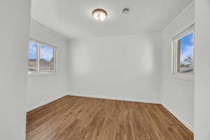 Empty room featuring visible vents, wood finished floors, and baseboards
