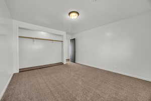 Unfurnished bedroom with carpet, a closet, and baseboards