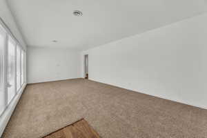 Spare room featuring baseboards, visible vents, and light colored carpet