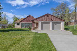 View of front of property featuring a front lawn, driveway, and fence