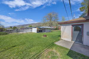 View of yard with fence, an outdoor structure, and a mountain view