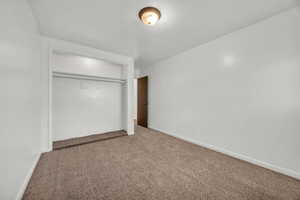 Unfurnished bedroom featuring a closet, carpet flooring, and baseboards