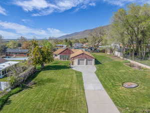 View of front of house with a residential view, a mountain view, concrete driveway, fence, and a front yard
