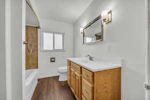 Bathroom with baseboards, wood finished floors, vanity, and toilet