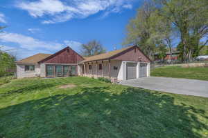 Ranch-style house featuring fence, a shingled roof, an attached garage, driveway, and a front yard