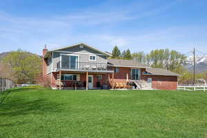 Back of property featuring a chimney, brick siding, fence, and a lawn