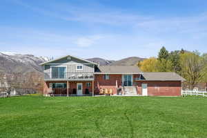 Back of property featuring brick siding, a mountain view, and a yard