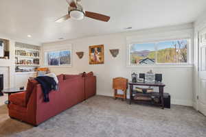 Carpeted living room featuring a fireplace, visible vents, a ceiling fan, and baseboards
