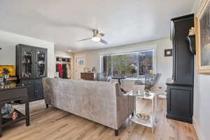 Living area featuring baseboards, a ceiling fan, and light wood-style floors