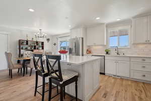 Kitchen featuring a kitchen breakfast bar, a sink, stainless steel appliances, light countertops, and visible vents